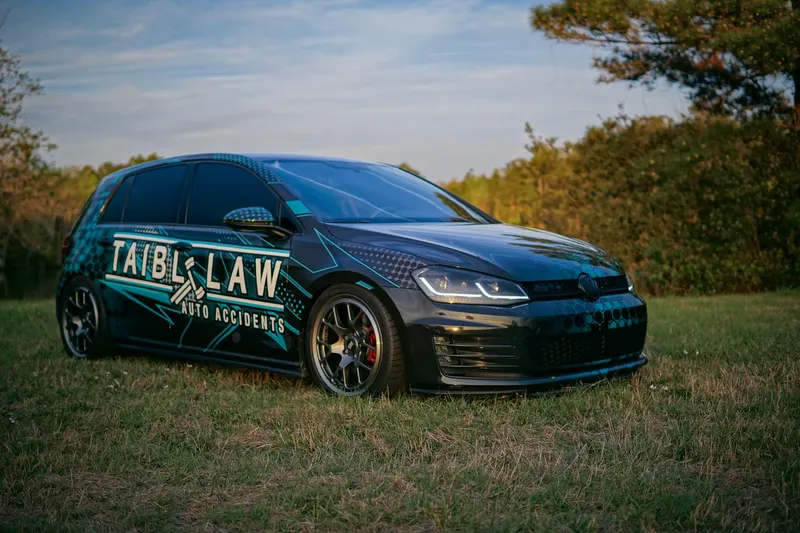 A Volkswagen car with custom tuning and legal advertisement parked on grassy lawn under clear sky.